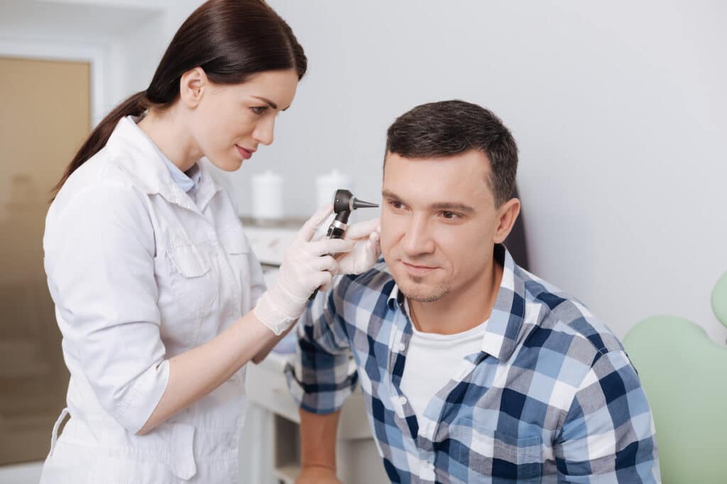 A doctor uses a tool to examine a patient's ears during a DOT Physical.
