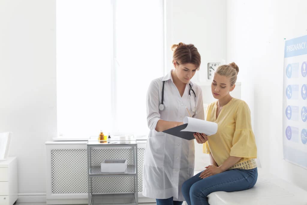 A doctor sharing STD Testing results with her patient and showing her her clipboard.