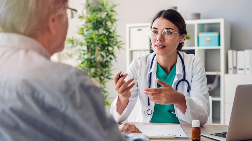 A doctor gestures to a patient as she explains results from a DOT Physical.