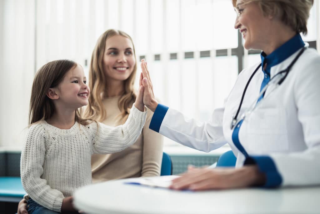A pediatrician giving a high five to a toddler after her appointment at My Kids Pediatric Clinic.