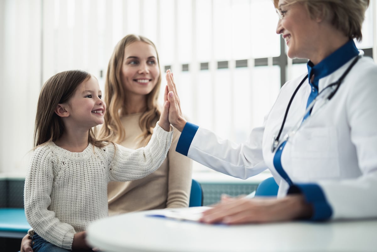 A pediatrician giving a high five to a toddler after her appointment at My Kids Pediatric Clinic.
