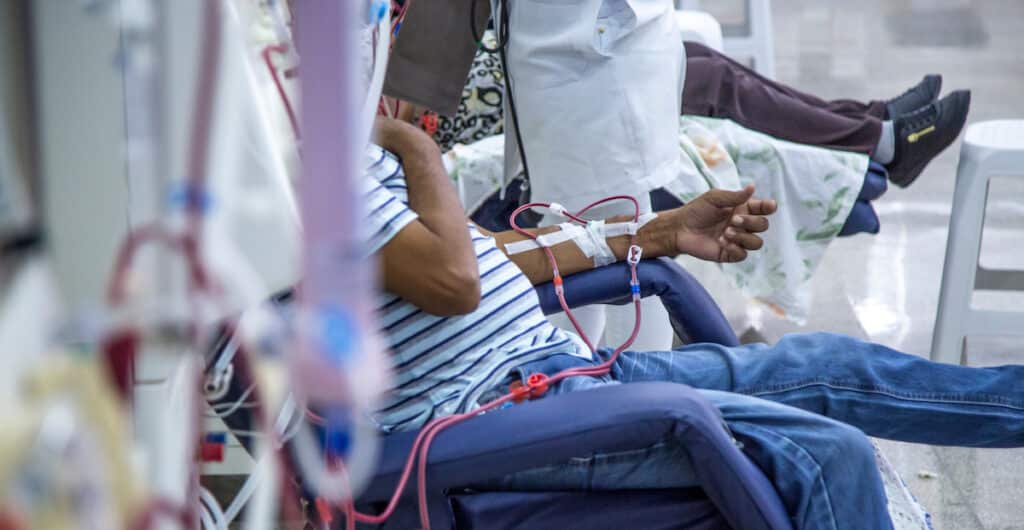 A patient sitting in a chair receiving treatment for chronic disease management.