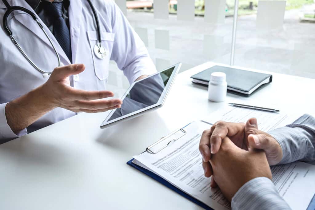 Two doctors discussing treatment plans and LGBTQ+ Care with each other in their office.