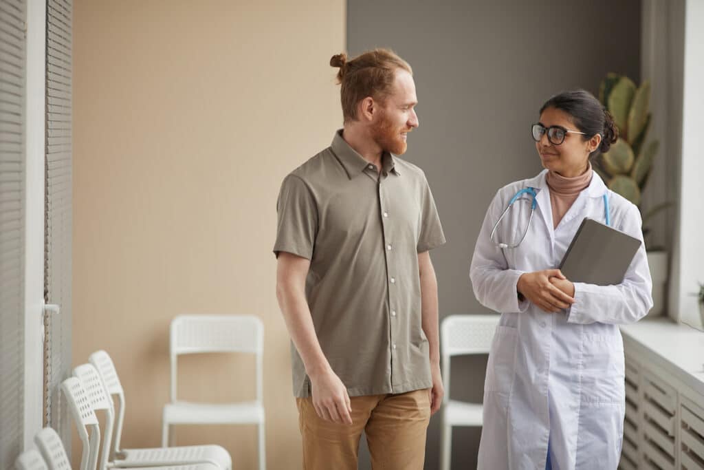 A primary care physician walking and talking to her patient.