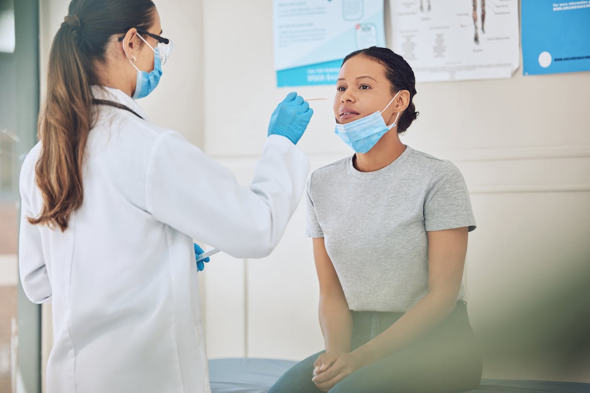 A doctor providing a COVID-19 test to a young female patient.