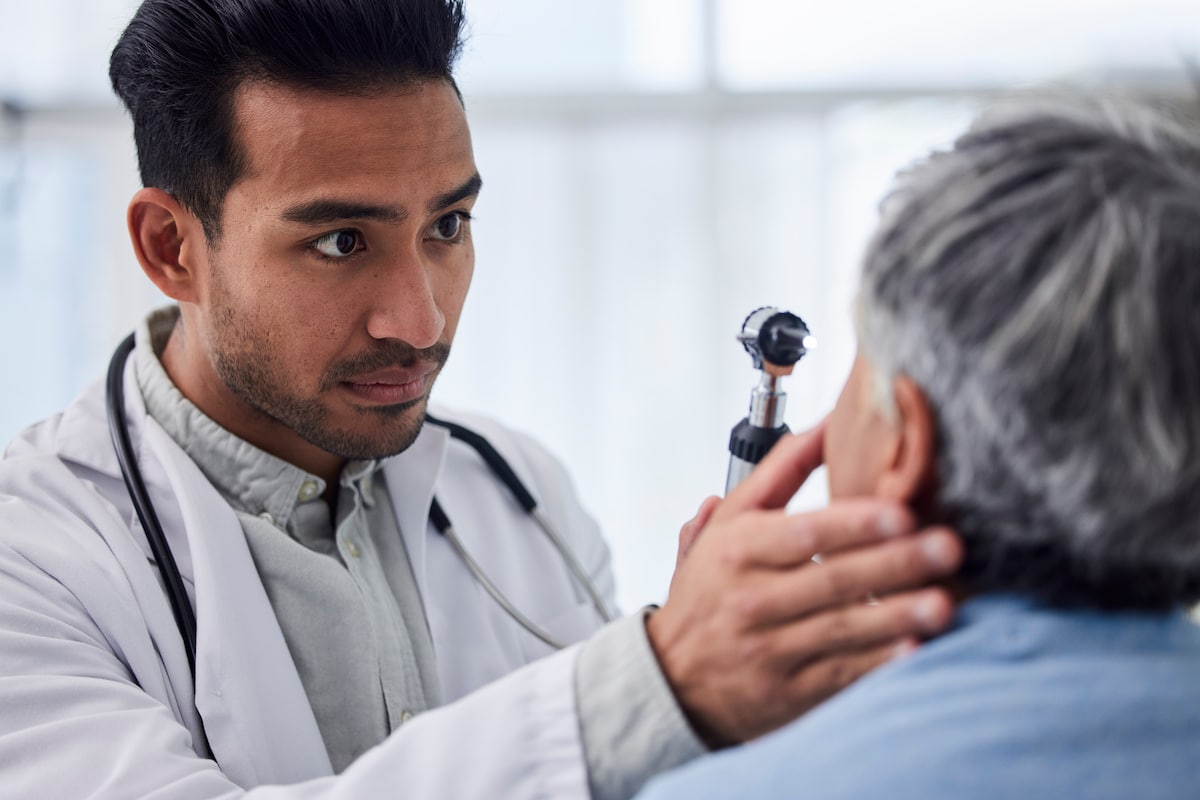 A man uses a light to examine the eyes of a patient during a DOT Physical.