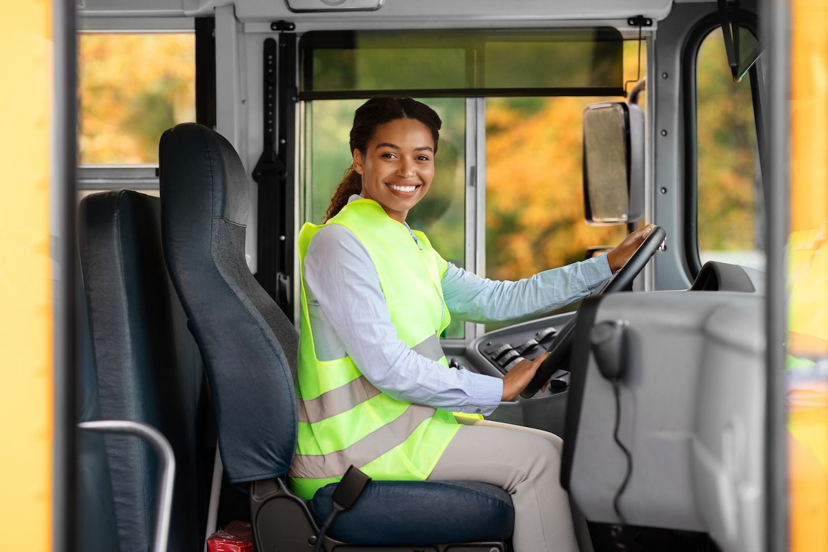 A bus driver smiling in her reflective vest after being cleared with her DOT Physicals.