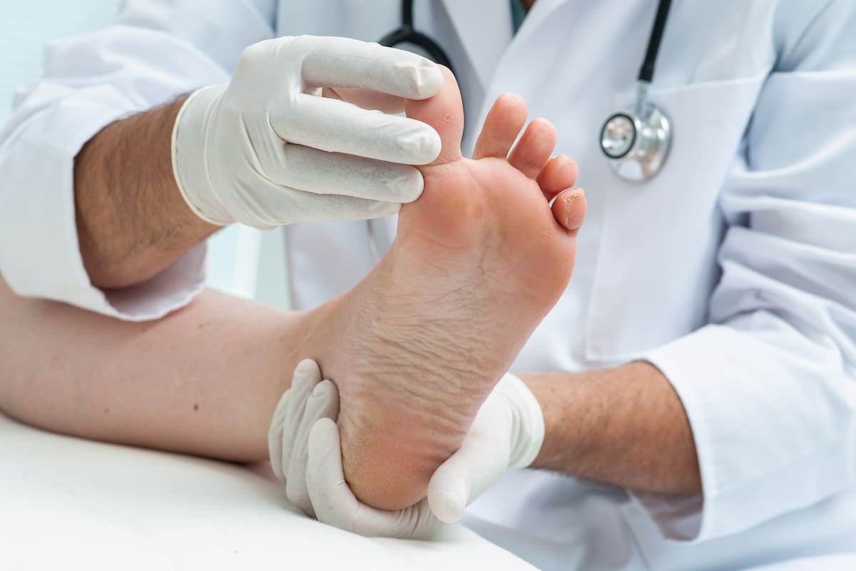 A podiatrist examines a patients foot, looking at the big toe.