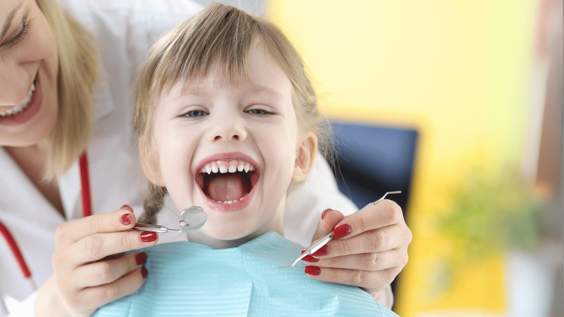 A dentist leaning around the back of a girl with a dental mirror and scraper. The little girl has a dentist bib on and her mouth is wide open.
