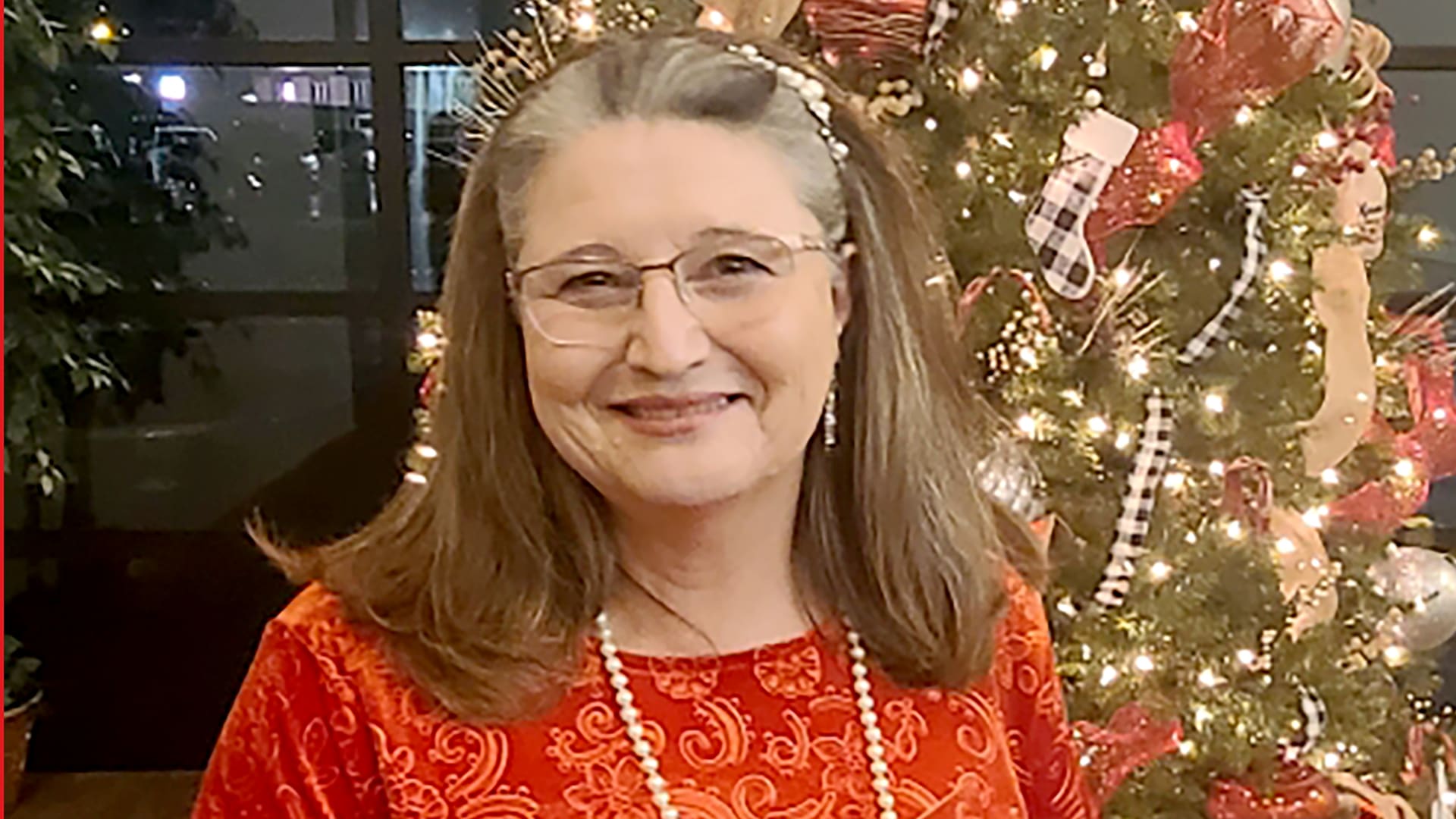 Phyllis Cunningham, a Healthy Connections member, poses in front of a Christmas tree.