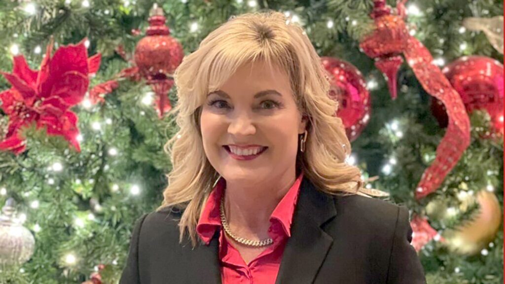 Susan Singleton, a Healthy Connections staff member, poses in front of a Christmas tree.