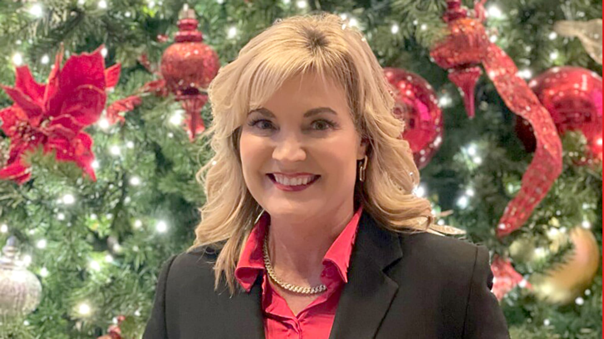 Susan Singleton, a Healthy Connections staff member, poses in front of a Christmas tree.