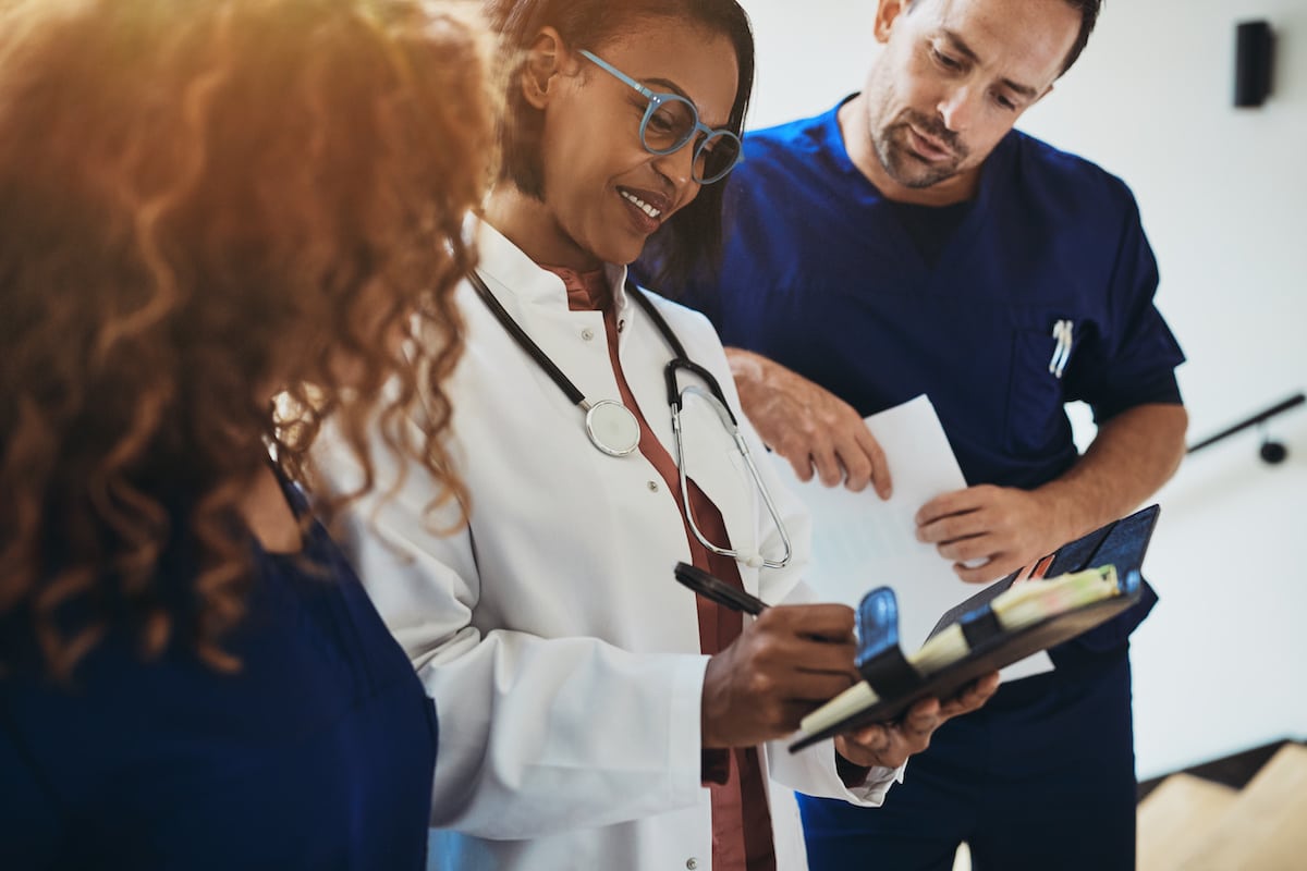 Smiling doctor talking with interns in a hospital corridor about a career in an FQHC.