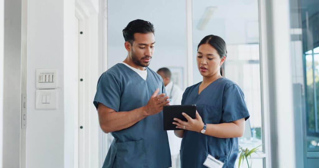 Men working in cardiology talking about surgery results on a tablet.