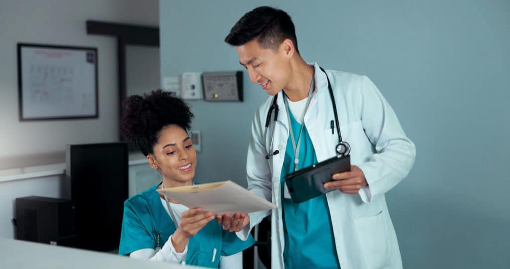 A doctor giving a file of information to a front desk worker at Healthy Connections.
