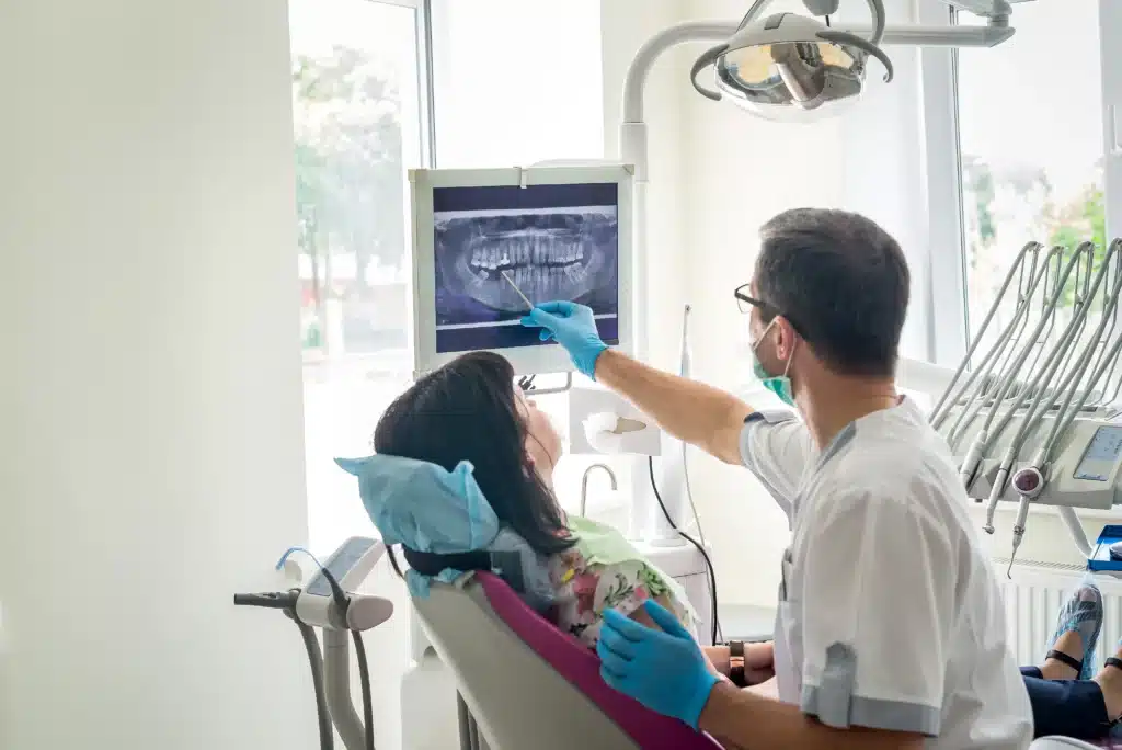 A dentist pointing out a tooth on an x-ray to his patient.