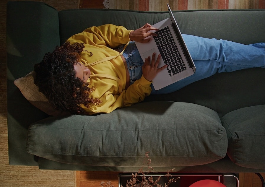 An above shot of a woman using her laptop on her sofa.